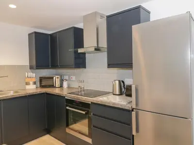 a kitchen with black cabinets and a stainless steel refrigerator at Dunaivon Cottage in Helensburgh