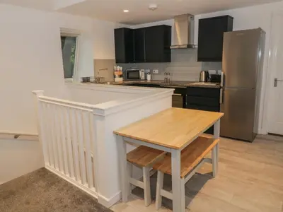 a kitchen with a wooden table and a refrigerator at Dunaivon Cottage in Helensburgh