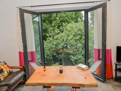 a living room with a table and a large window at Dunaivon Cottage in Helensburgh