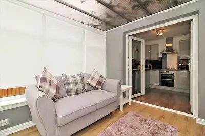 a living room with a couch and a kitchen at Signature - Culzean House in Newarthill
