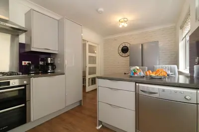 a kitchen with white cabinets and a counter top at Signature - Culzean House in Newarthill