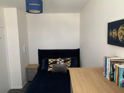 a bedroom with a bed and a table and books at The Cochno Flat, Clydebank in Dalmuir