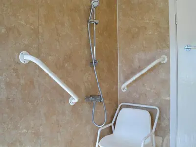 a shower with a white chair in a bathroom at Kinvara in Stranraer