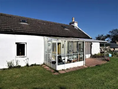 a white house with glass doors and a yard at Tigh Na Maraiche in Isle of Jura