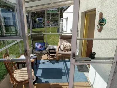 a screened in porch with chairs and a table at Tigh Na Maraiche in Isle of Jura