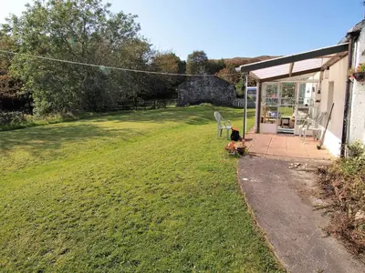 a person sitting on a bench in a yard at Tigh Na Maraiche in Isle of Jura
