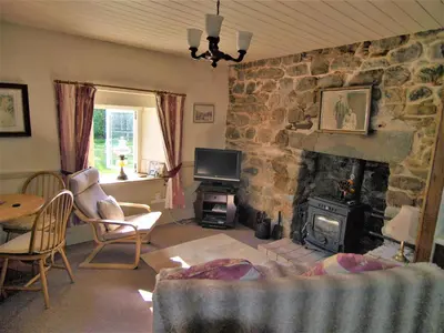 a living room with a stone fireplace and a tv at Tigh Na Maraiche in Isle of Jura