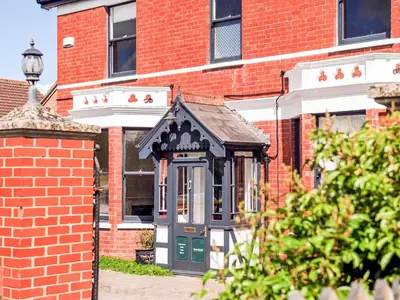 a small building with a green door in front of a brick building at Holst Apartment in Newton Stewart