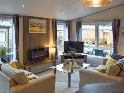 a living room with two couches and a tv at Riverside Lodge in Auchterarder