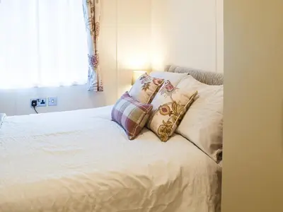 a bedroom with a bed with pillows on it at Riverside Lodge in Auchterarder