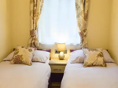 two beds in a room with a window at Riverside Lodge in Auchterarder