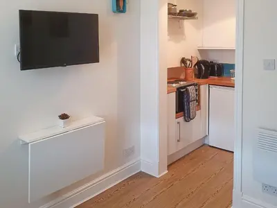 a kitchen with white cabinets and a flat screen tv on the wall at Osocozee in Millport