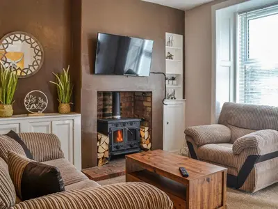 a living room with a fireplace with a tv above it at Sunnyside in New Galloway