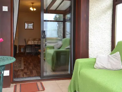 a living room with a green couch and a glass door at Ashley Cottage in Bowmore