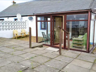 a conservatory with sliding glass doors on a house at Ashley Cottage in Bowmore