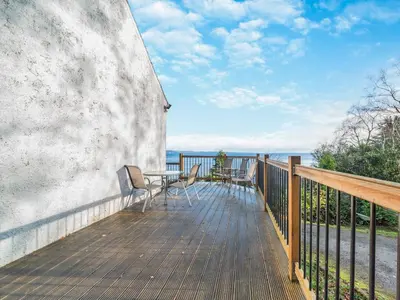 a wooden deck with a table and chairs on it at The Creagan in Corrie