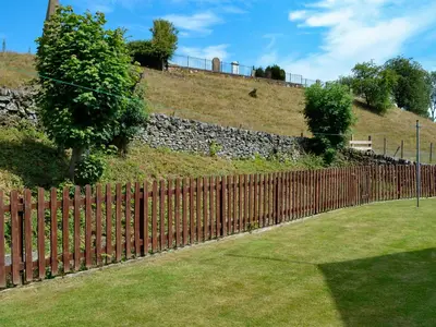 a wooden fence in front of a hill at Westlin in Penpont