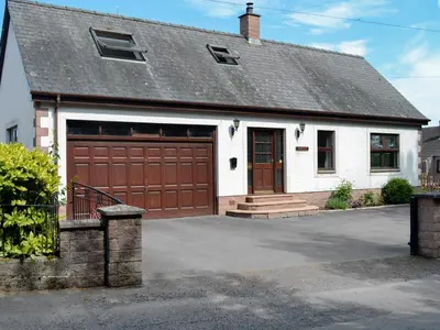 a white house with a brown garage door at Westlin in Penpont