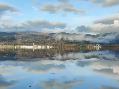 a view of a lake with trees and clouds in the water at Willow Lodge in Rashfield