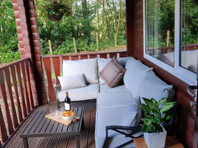 a white couch on a porch with a bottle of wine at Willow Lodge in Rashfield