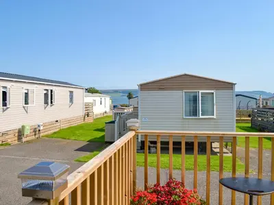 a mobile home with a deck and a house at Loch View in Kirkcolm