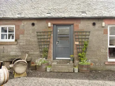 a brick house with a gray door and potted plants at The Barn in Fintry