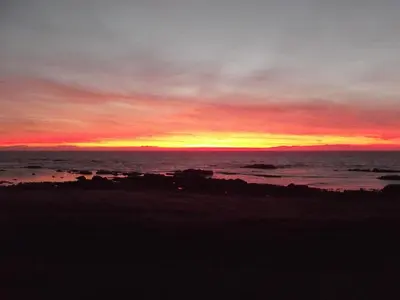 a sunset on the beach with the ocean at Shore Cottage in Bellochantuy
