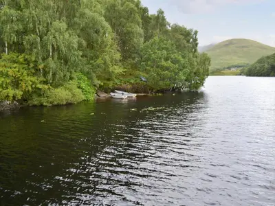 a river with trees and a boat in the water at Faodail-Uk34218 in Aberfoyle