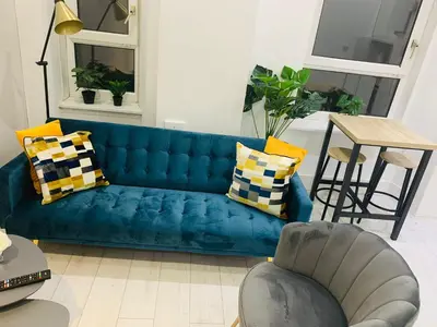 a blue couch in a living room with a table at Cheerful 2 Bedroom Homely Apartment, Sleeps 4 Guest Comfy, 3x Double Bed, Parking, Free WiFi, Suitable For Business, Leisure Guest,Glasgow, Glasgow West End, Near City Centre, Perfect For Common Wealth Games 2026 in Glasgow