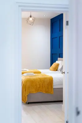 a bedroom with a bed with a blue door at Cheerful 2 Bedroom Homely Apartment, Sleeps 4 Guest Comfy, 3x Double Bed, Parking, Free WiFi, Suitable For Business, Leisure Guest,Glasgow, Glasgow West End, Near City Centre, Perfect For Common Wealth Games 2026 in Glasgow