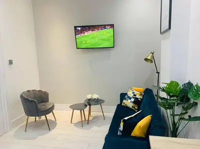 a living room with a blue couch and a tv on the wall at Cheerful 2 Bedroom Homely Apartment, Sleeps 4 Guest Comfy, 3x Double Bed, Parking, Free WiFi, Suitable For Business, Leisure Guest,Glasgow, Glasgow West End, Near City Centre, Perfect For Common Wealth Games 2026 in Glasgow