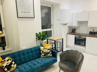 a living room with a blue couch and a chair at Cheerful 2 Bedroom Homely Apartment, Sleeps 4 Guest Comfy, 3x Double Bed, Parking, Free WiFi, Suitable For Business, Leisure Guest,Glasgow, Glasgow West End, Near City Centre, Perfect For Common Wealth Games 2026 in Glasgow