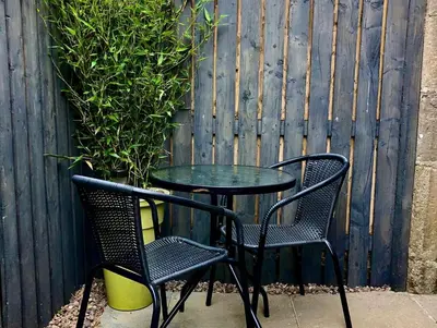 a table and two chairs next to a fence at Trossachs Barn & Cabin - boutique B&B in Port of Menteith