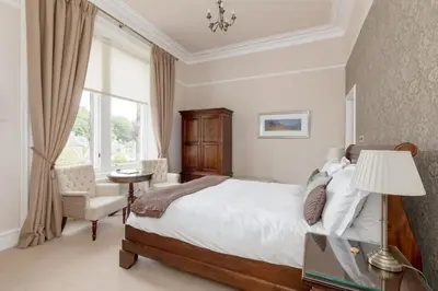 a bedroom with a bed and a chair and a window at Victoria Square & The Orangery in Stirling