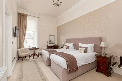 a bedroom with a large bed and a table at Victoria Square & The Orangery in Stirling