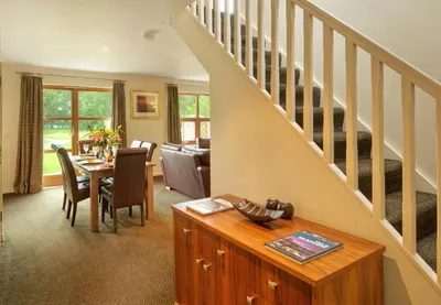 a living room with a table and a staircase at Loch Lomond Waterfront Luxury Lodges in Balmaha