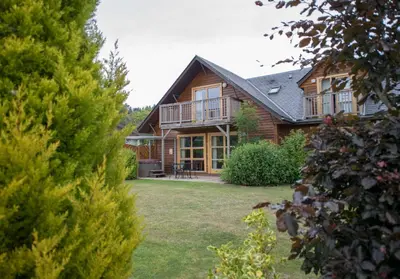 a large wooden house with a yard at Loch Lomond Waterfront Luxury Lodges in Balmaha
