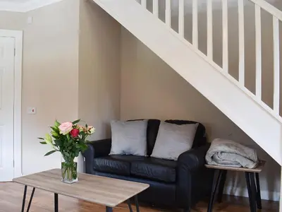 a living room with a black couch and a table at Fascadail-Uk34219 in Aberfoyle