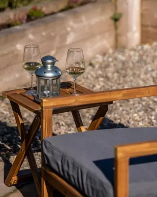 two glasses of wine sitting on a wooden table at Luxury Glamping Pods - The Heft & The Hirsel in Glasgow