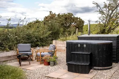 a patio with a table and two chairs and a wooden table at Luxury Glamping Pods - The Heft & The Hirsel in Glasgow