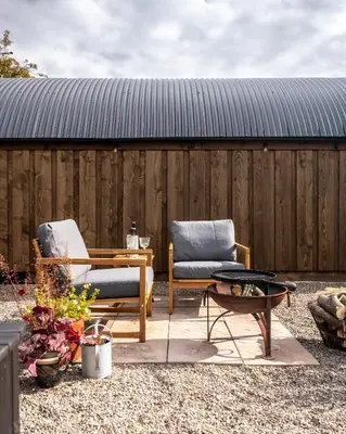 a patio with two chairs and a table and a fence at Luxury Glamping Pods - The Heft & The Hirsel in Glasgow