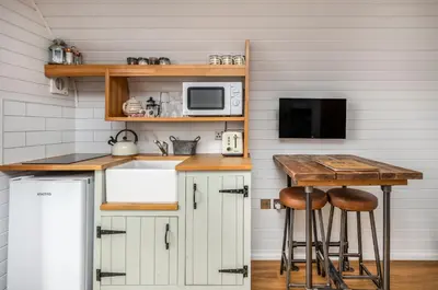 a kitchen with white cabinets and a table and a microwave at Luxury Glamping Pods - The Heft & The Hirsel in Glasgow