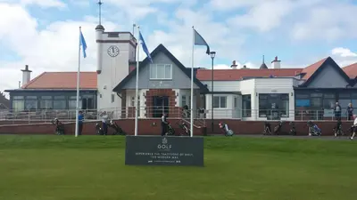 a building with a clock tower and a sign in the grass at Troon Beach Town Golf Apartment Troon Ayrshire in Troon