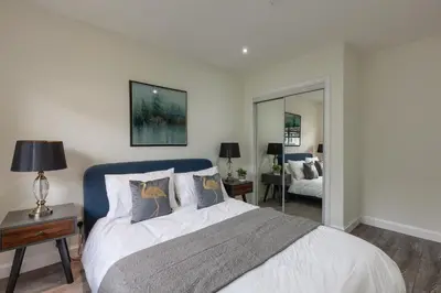 a bedroom with a bed with a blue headboard and a mirror at 3 bedroom Windsor Garden apartment by Gleneagles in Blackford