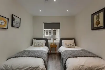 two twin beds in a room with white walls at 3 bedroom Windsor Garden apartment by Gleneagles in Blackford
