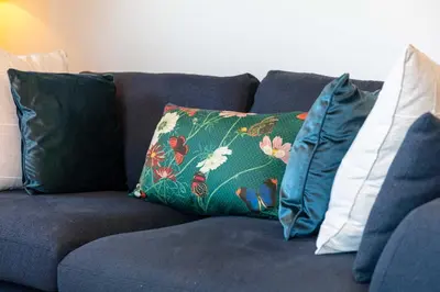 a blue couch with three pillows on it at The Orchard - Donnini Apartments in Ayr