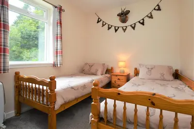 two twin beds in a room with a window at Nursery Cottage Benmore in Benmore