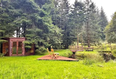 a picnic table and a chair on a rug in a field at Nursery Cottage Benmore in Benmore
