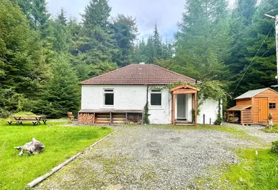 a white house in a yard with a picnic table at Nursery Cottage Benmore in Benmore