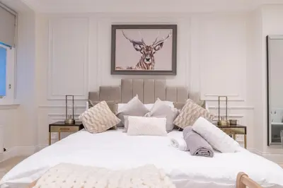 a bedroom with a large white bed with a deer picture on the wall at Large Blythswood Residence in Glasgow